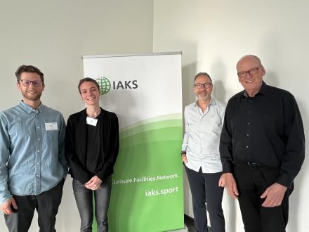 4 Personen vor IAKS Schild